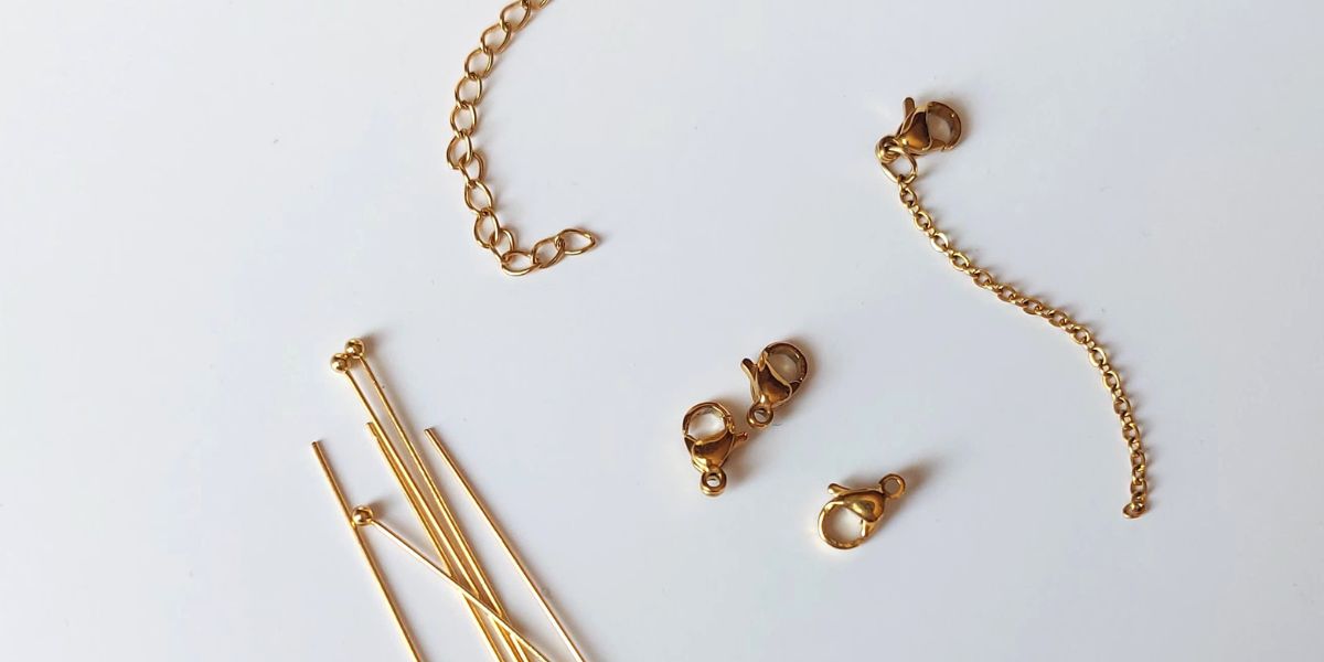 Matériaux de fabrication de bijoux dorés posés sur un fond blanc