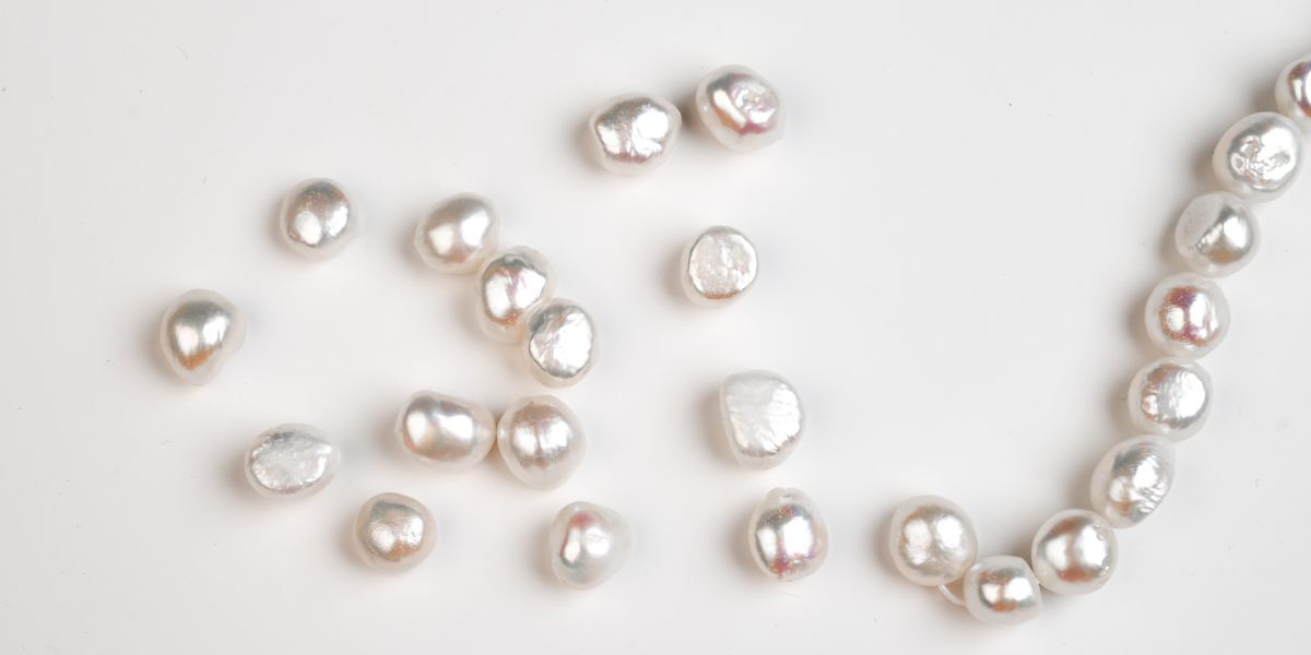 Perles d'eau douce blanches dispersées sur un fond blanc.