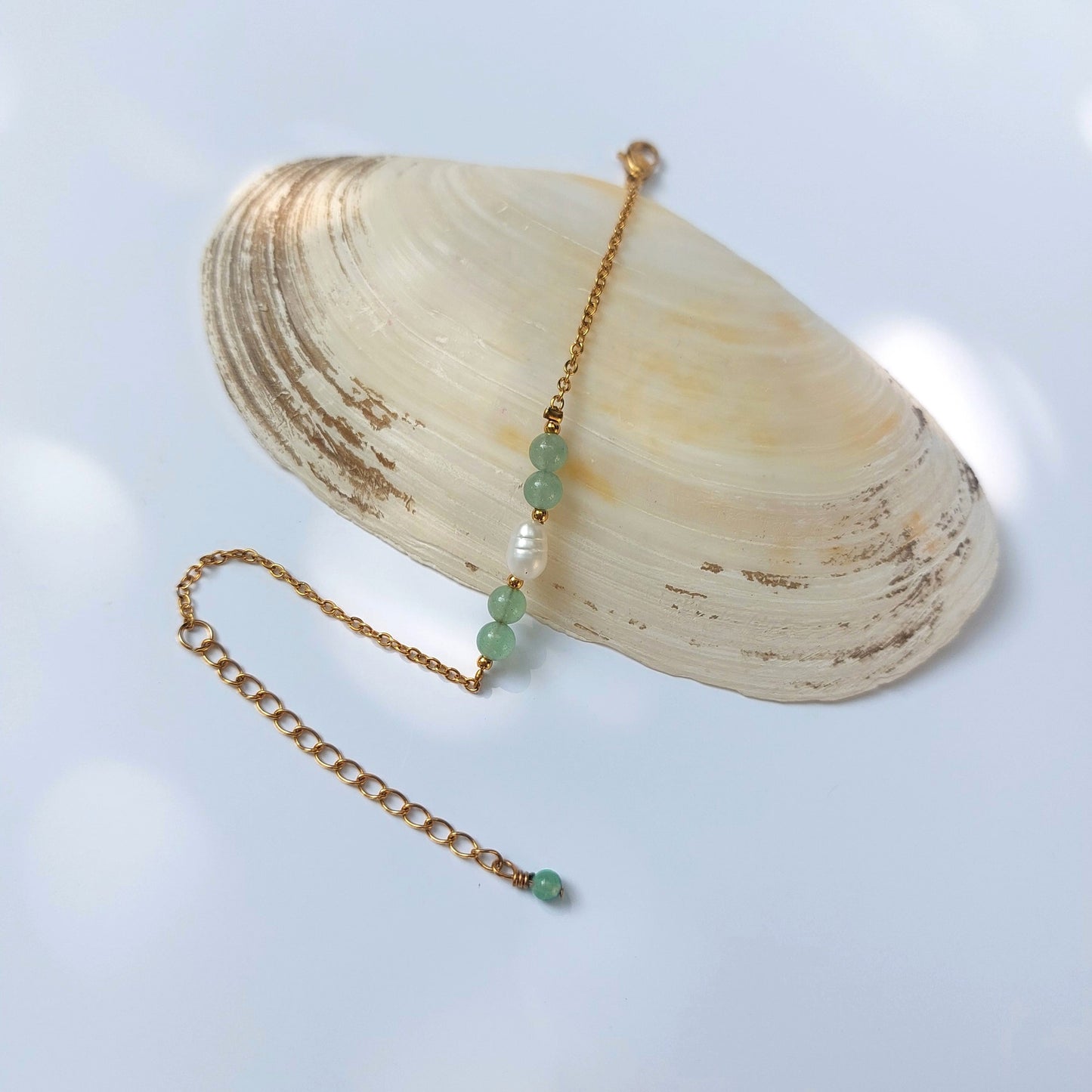 Bracelet élégant Acropora en perle d'eau douce et perles d'aventurine verte posé sur fond gris.
