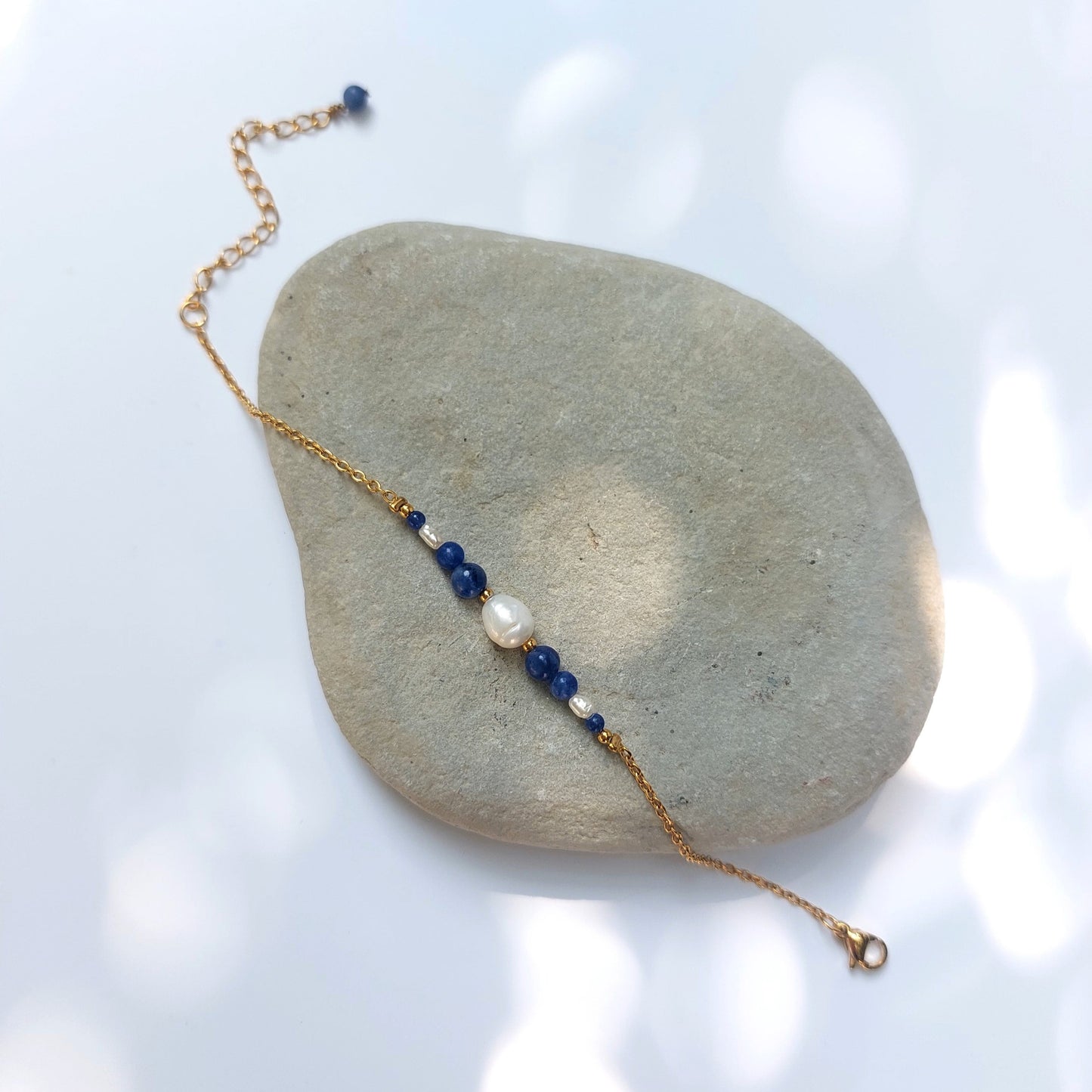Bracelet Anthelia en perles d'eau douce et perles de sodalite bleue posé sur fond gris.
