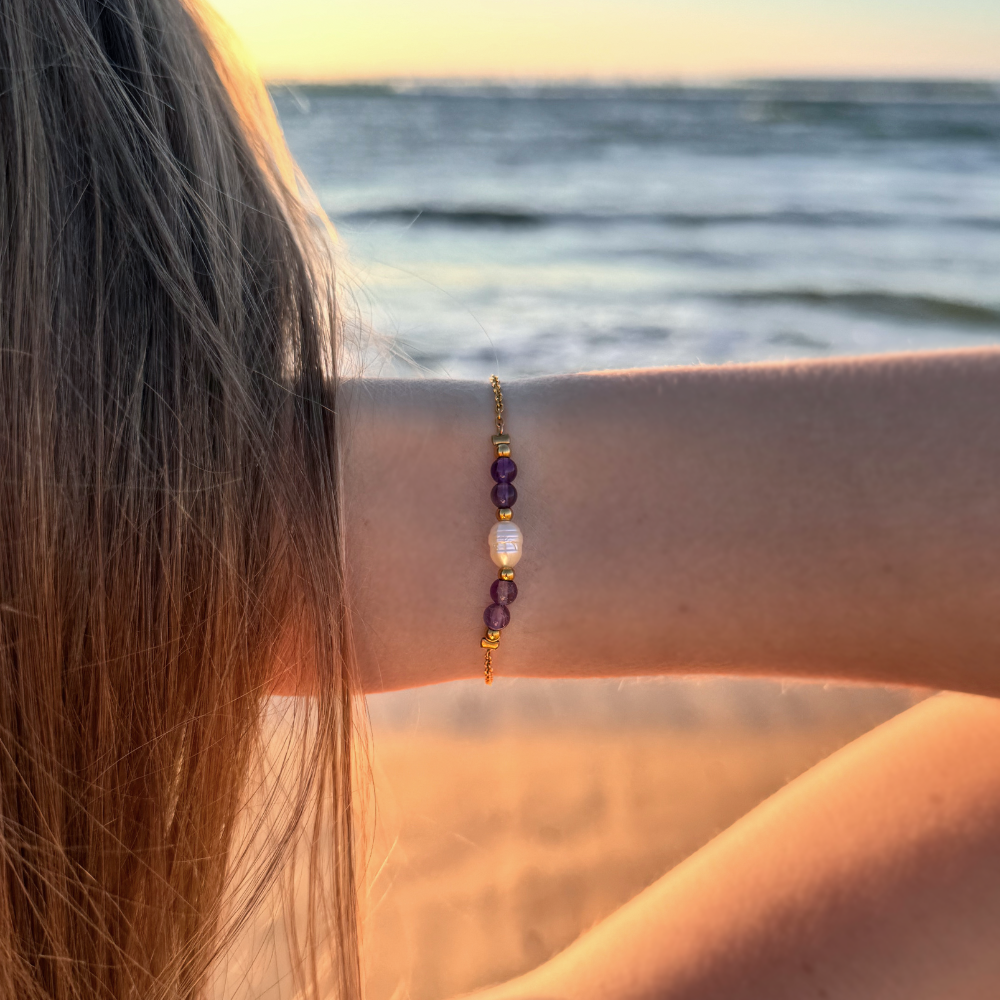 Bracelet en acier inoxydable avec perle d'eau douce et perles de couleur porté par une femme devant un coucher de soleil.