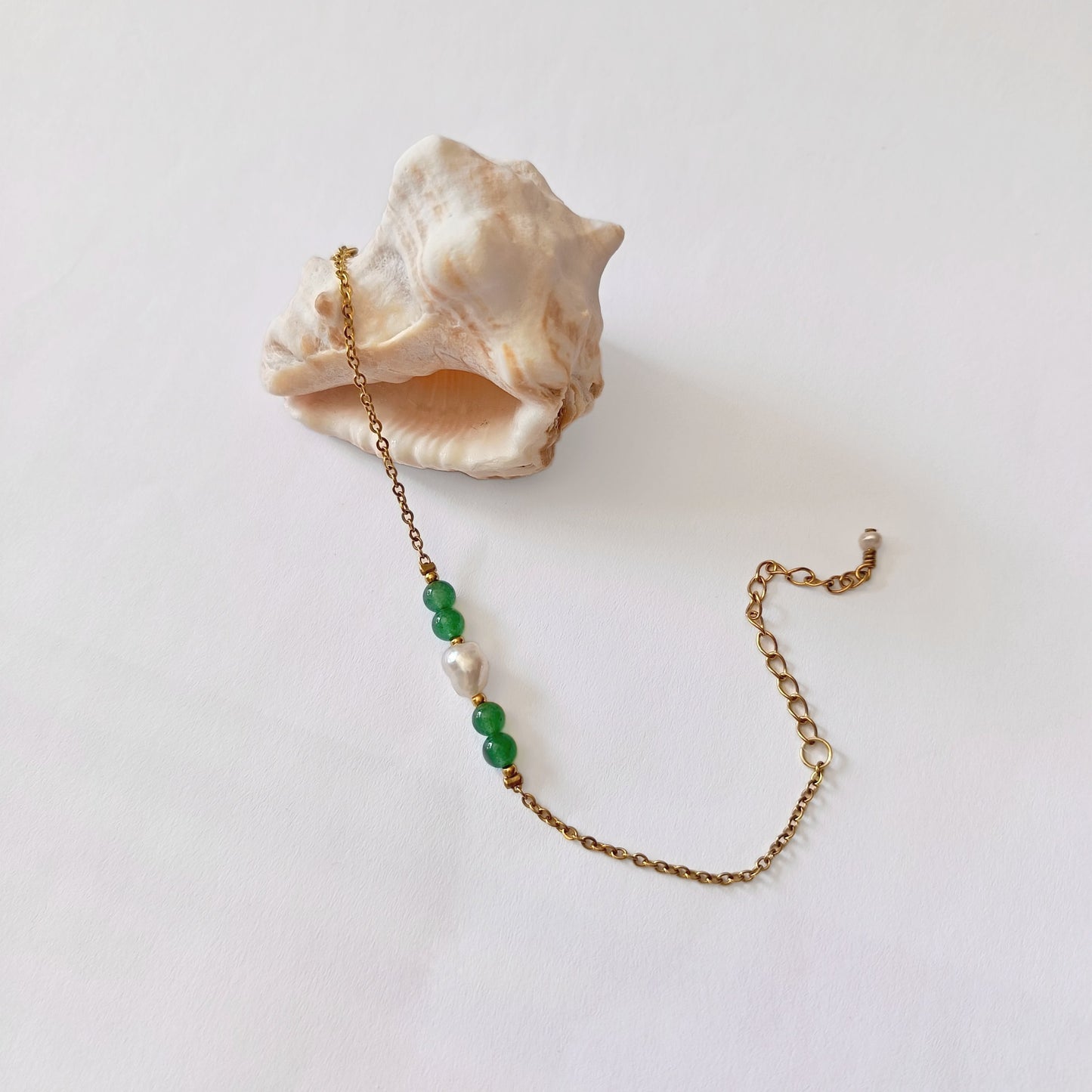 Bracelet élégant Acropora en perle d'eau douce et perles d'aventurine verte posé sur fond blanc.