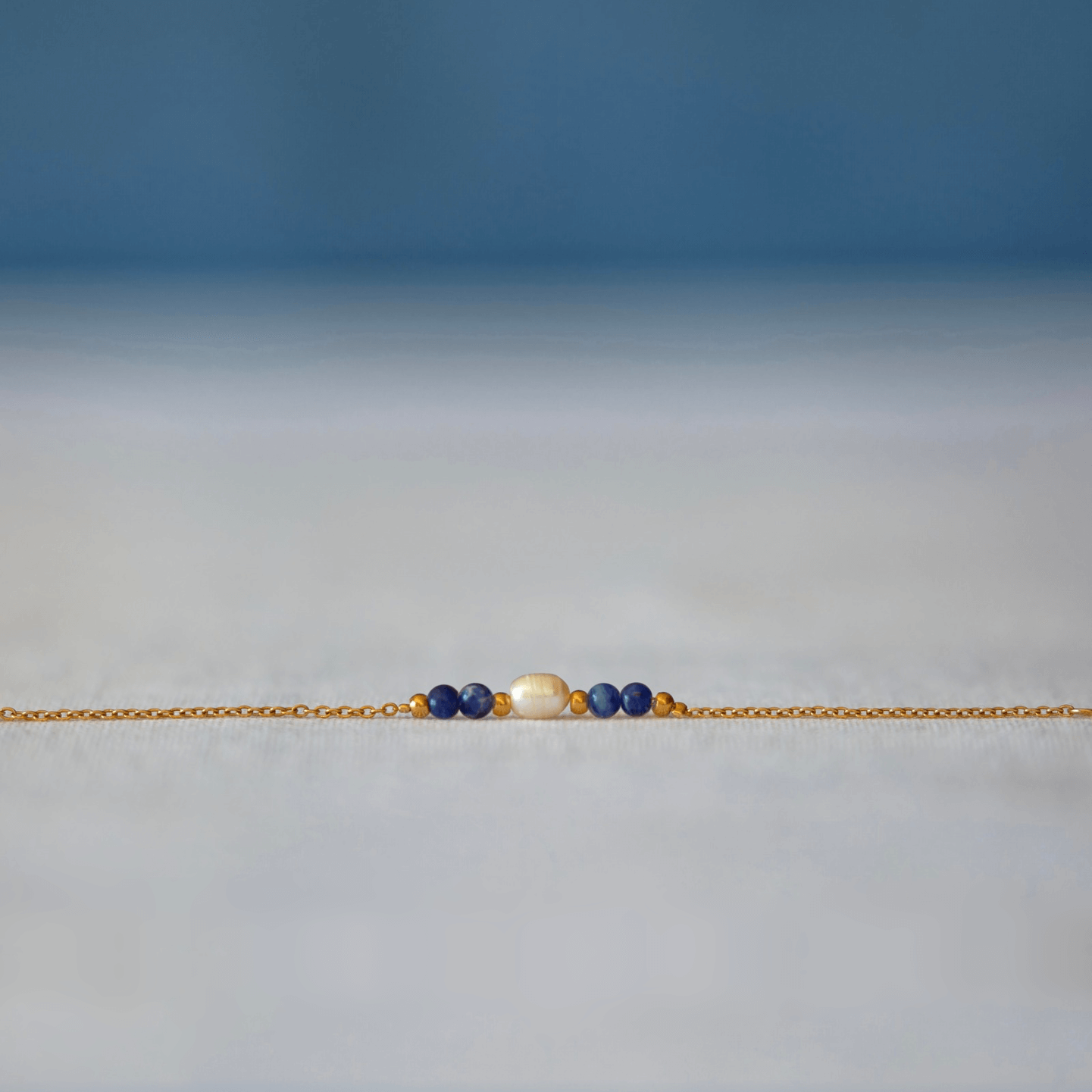 Bracelet élégant Acropora en perle d'eau douce et perles de sodalite bleu posé sur fond gris.