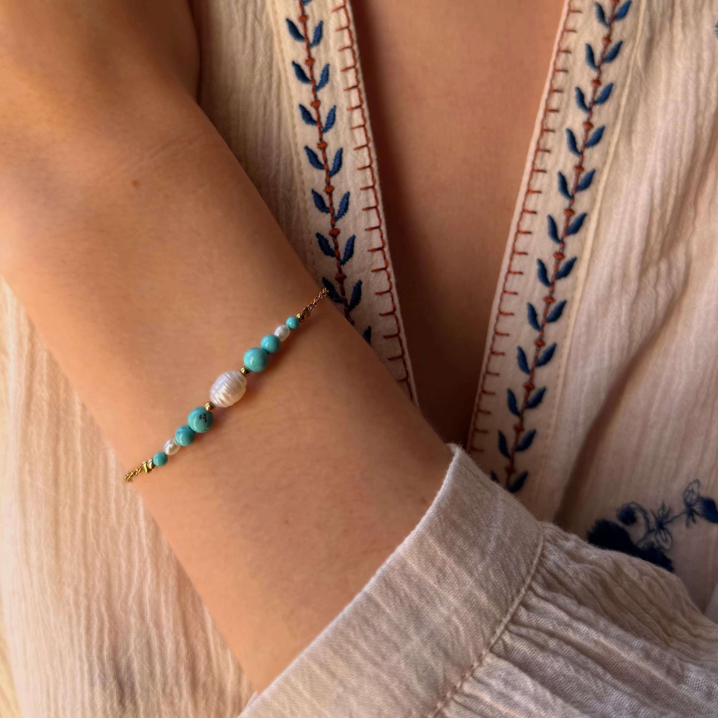 Bracelet en acier inoxydable et perles naturelles porté par une femme.