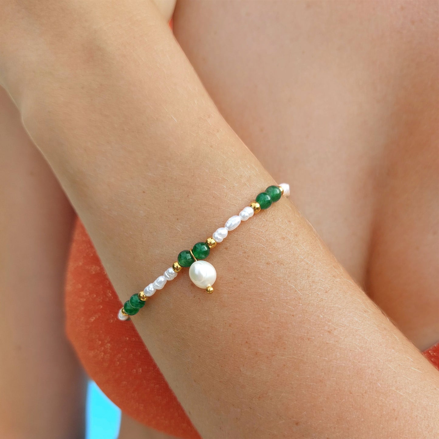 Bracelet en acier inoxydable, perles d'eau douce et pierres naturelles vertes porté par une femme.