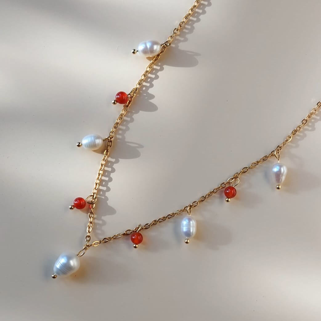 Collier en acier inoxydable orné de plusieurs perles d'eau douces et perles de cornaline oranges.