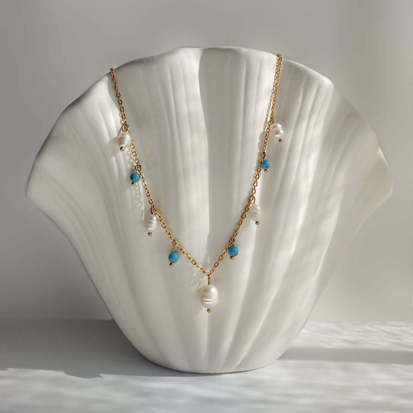 Collier Meandrina en perles d'eau douce et perles de turquoise posé sur fond blanc