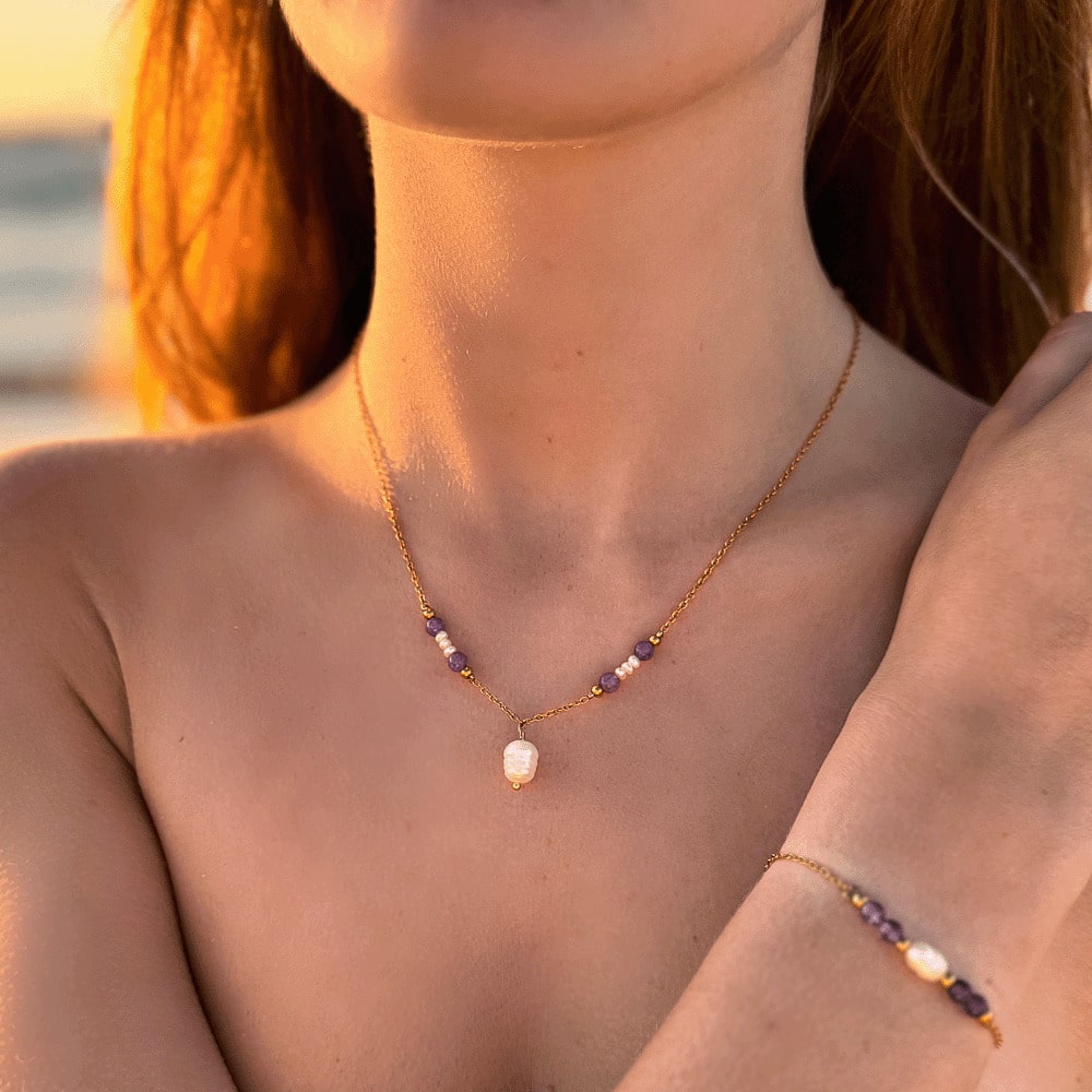 Collier pendentif en acier inoxydable avec perles d'eau douce et perles de couleur porté par une femme devant l'océan.