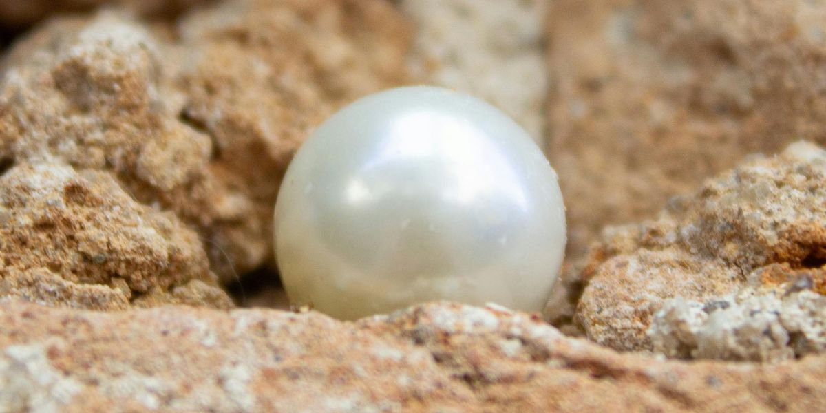 Une perle blanche brillante posée sur une surface rocheuse rugueuse.