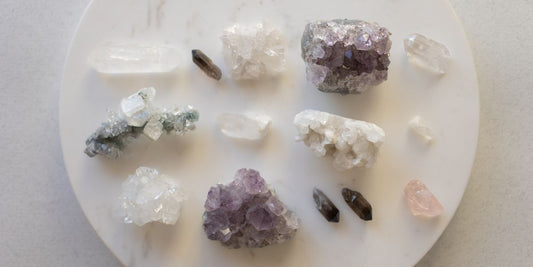 Vue du dessus d'une collection de cristaux variés disposés sur un plateau circulaire en marbre blanc.