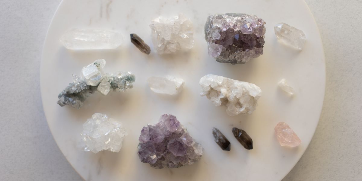 Vue du dessus d'une collection de cristaux variés disposés sur un plateau circulaire en marbre blanc.