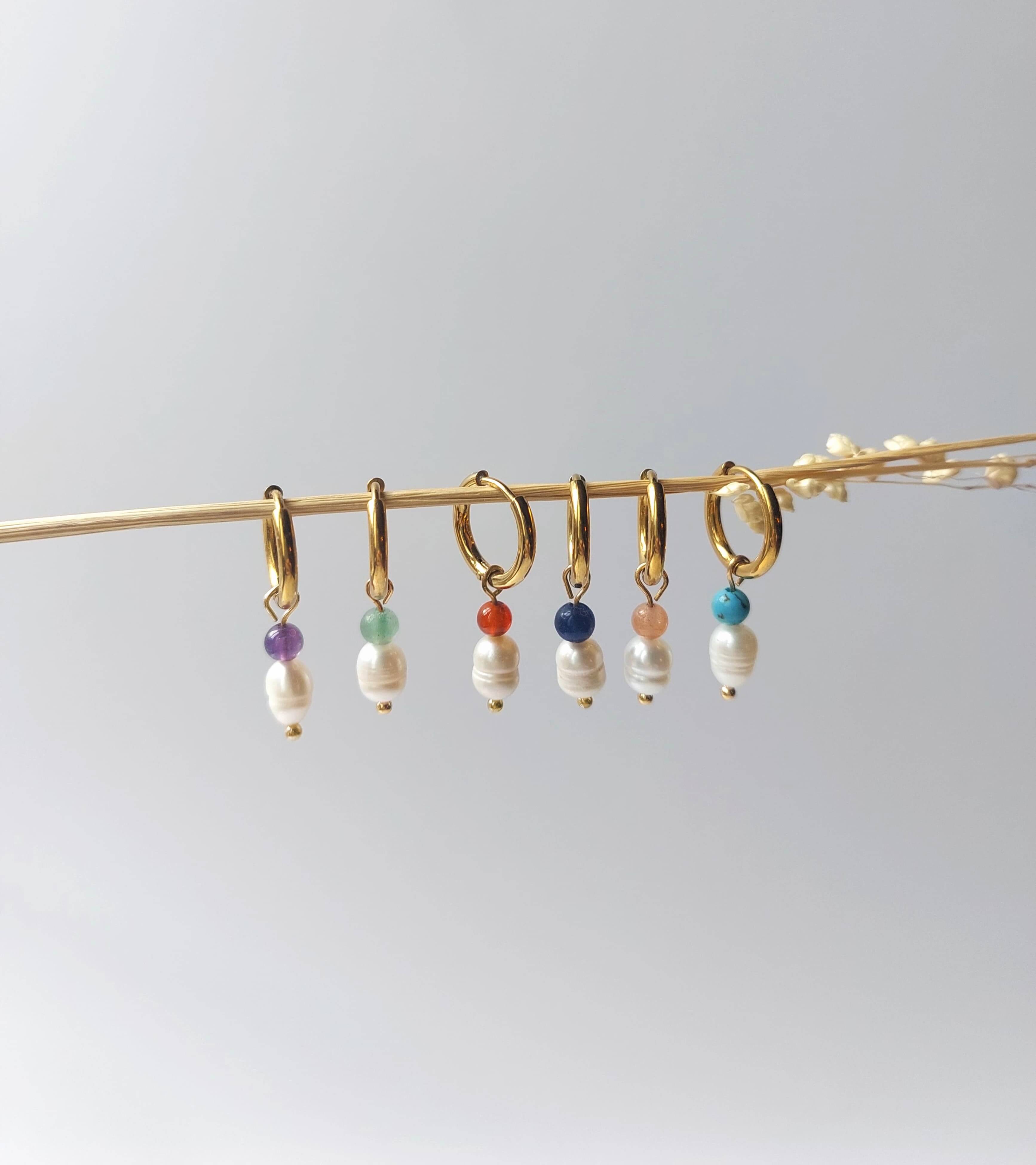 Boucles d'oreilles créole en acier inoxydable, perles d'eau douce et pierres naturelles posées sur une branche