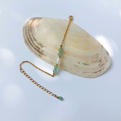 Bracelet élégant Acropora en perle d'eau douce et perles d'aventurine verte  posé sur fond gris.