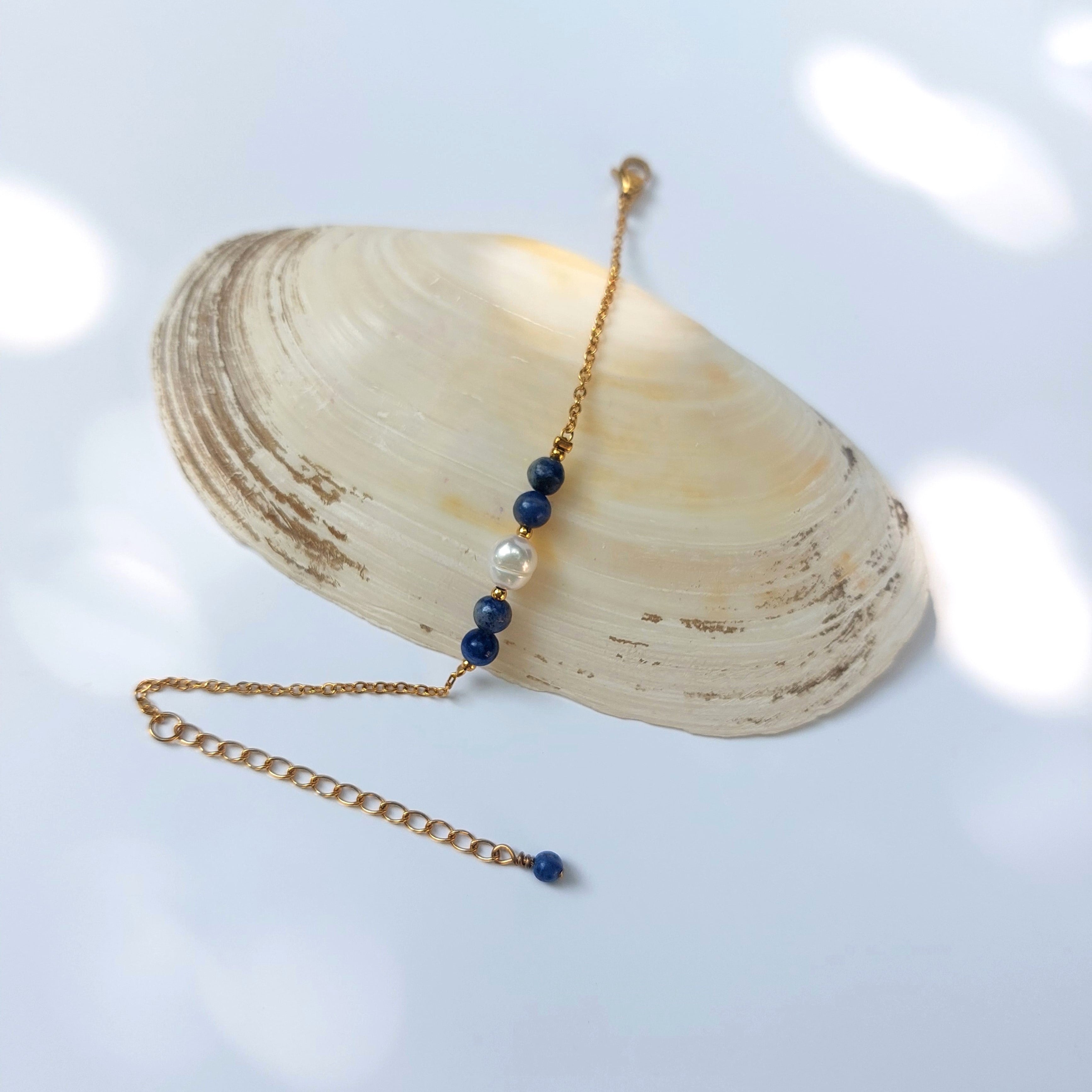 Bracelet élégant Acropora en perle d'eau douce et perles de sodalite bleu posé sur fond gris.