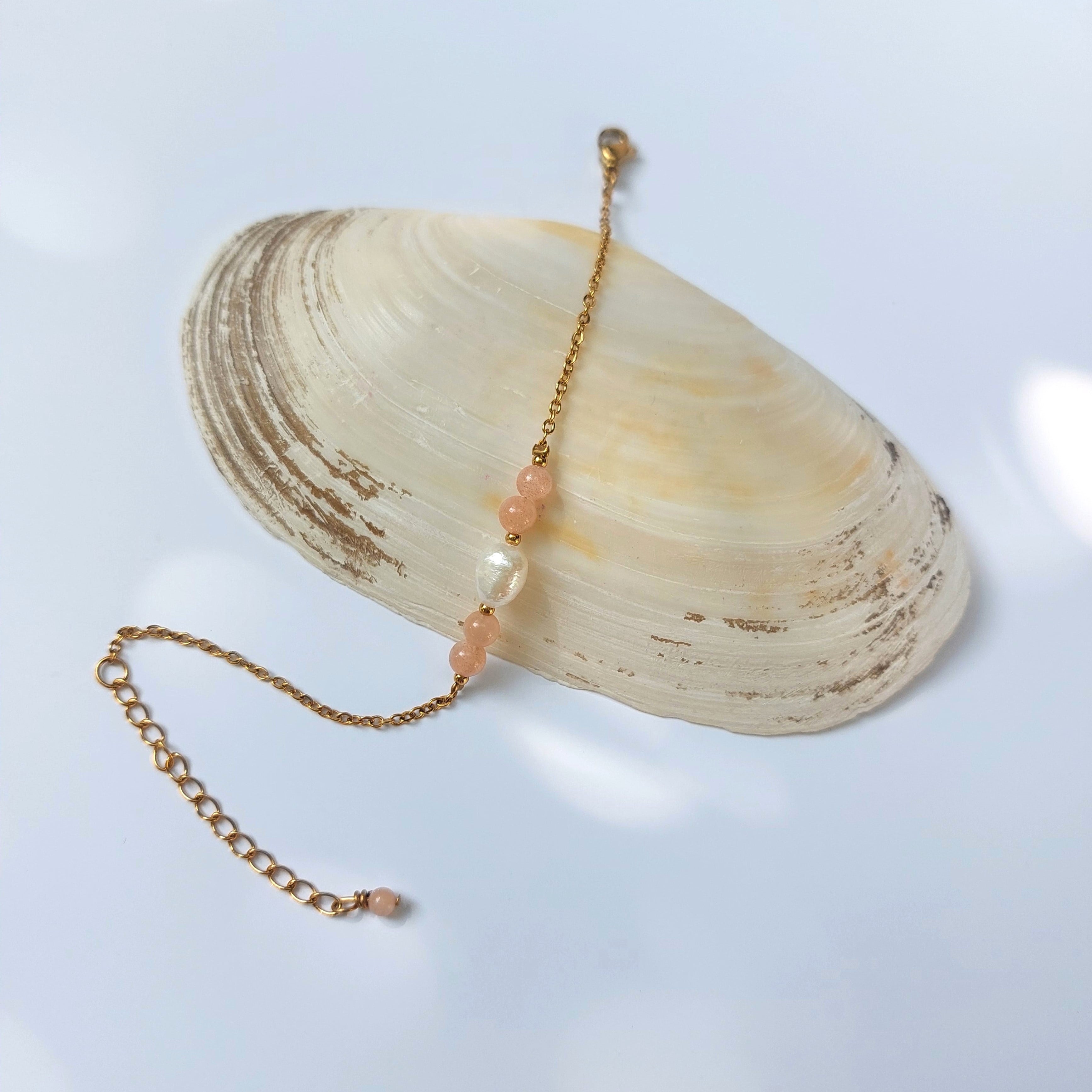 Bracelet élégant Acropora en perle d'eau douce et perles de pierre de soleil posé sur fond gris.