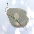 Bracelet Anthelia en perles d'eau douce et perles d'aventurine verte posé sur fond gris.