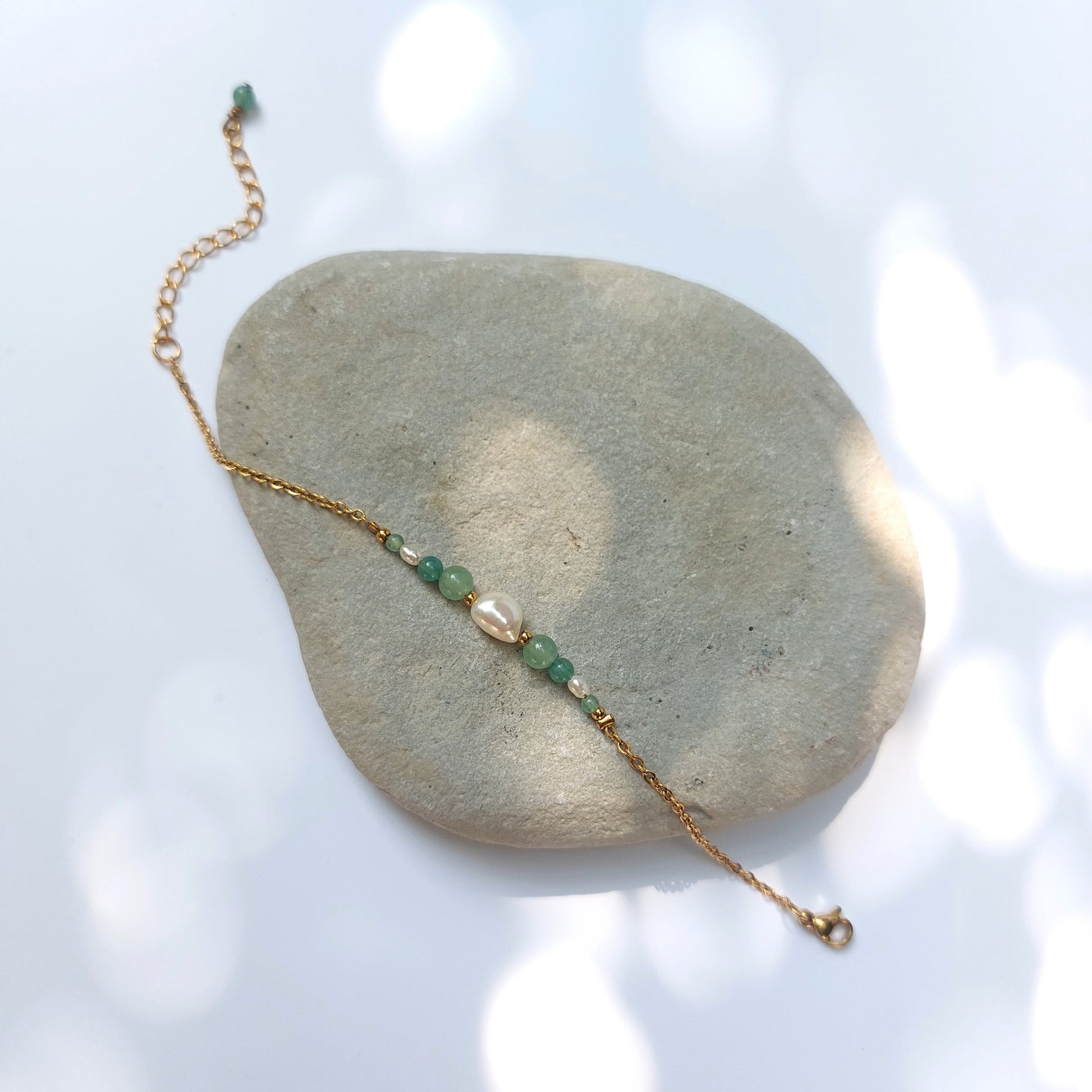 Bracelet Anthelia en perles d'eau douce et perles d'aventurine verte posé sur fond gris.