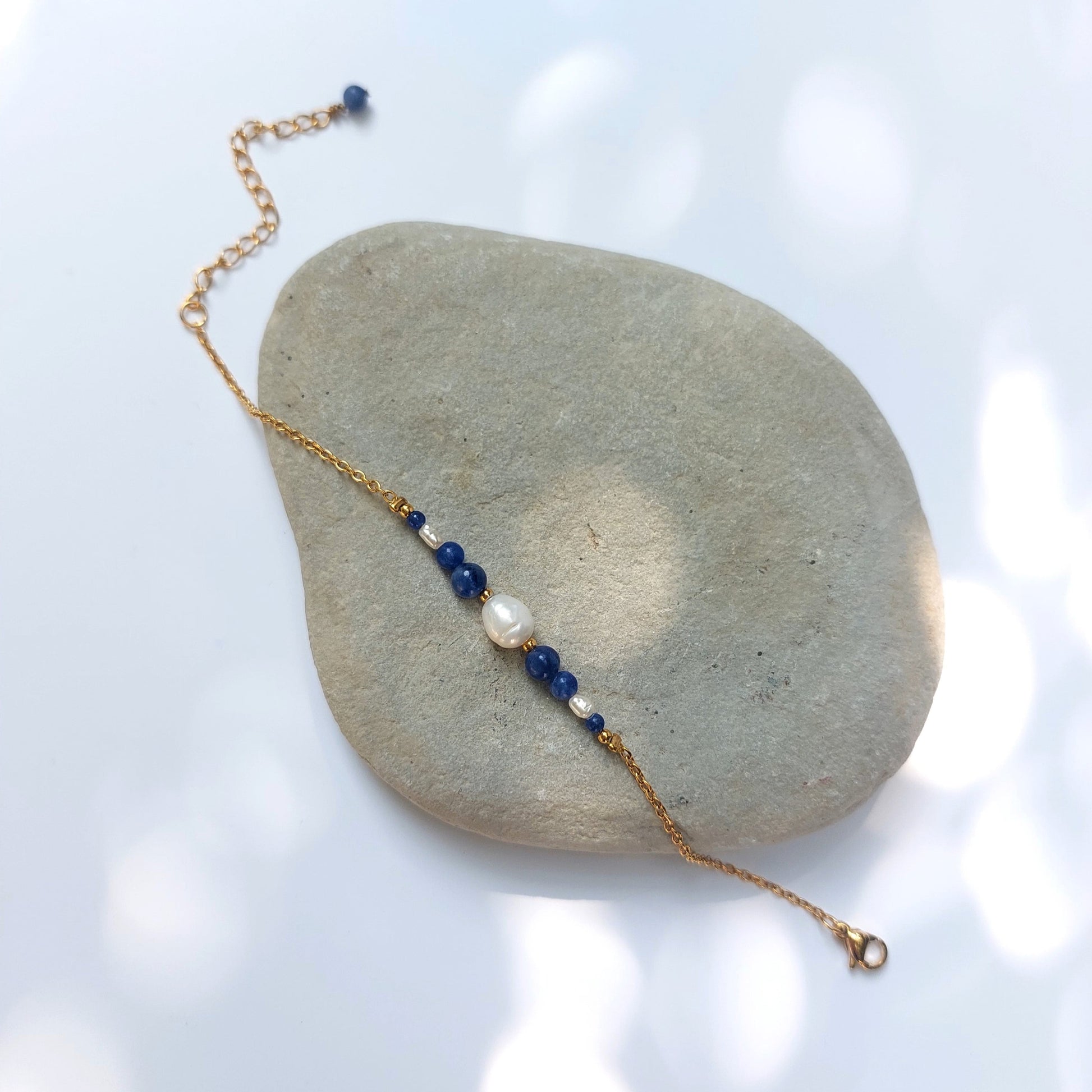 Bracelet Anthelia en perles d'eau douce et perles de sodalite bleue posé sur fond gris.