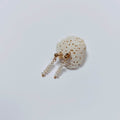 Boucles d’oreilles pendantes en perles d’eau douce naturelles blanches et acier inoxydable doré, au design linéaire et contemporain, accrochées à morceau de corail blanc, sur fond neutre.