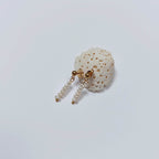 Boucles d’oreilles pendantes en perles d’eau douce naturelles blanches et acier inoxydable doré, au design linéaire et contemporain, accrochées à morceau de corail blanc, sur fond neutre.