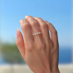 Bague portée, ornée de petites perles d'eau douce naturelles blanches, sur fond bleu. 