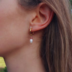 Boucle d'oreille créole en acier inoxydable avec perle d'eau douce et quartz fraise portée par une femme