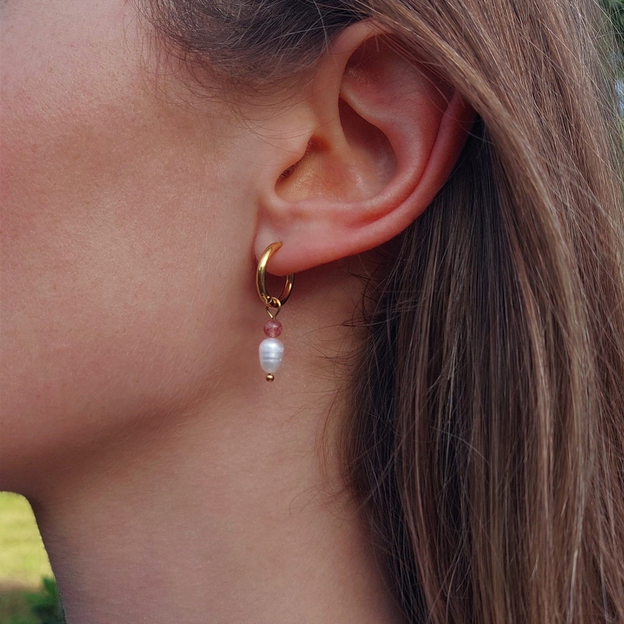 Boucle d'oreille créole en acier inoxydable avec perle d'eau douce et quartz fraise portée par une femme