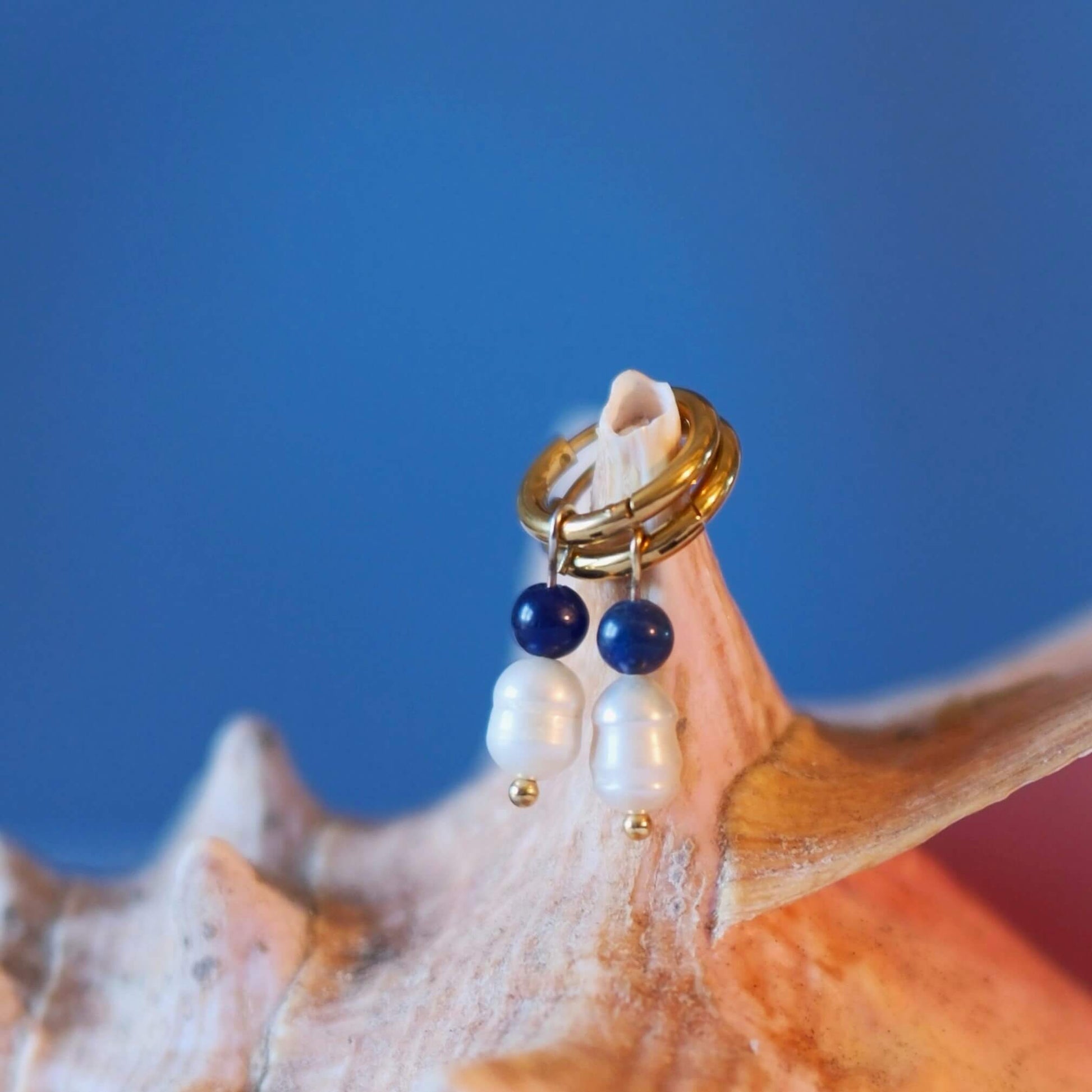 Boucles d'oreilles créoles en acier inoxydable avec une pierre d'eau douce et une perle de sodalite bleue. Design minimaliste et coloré.