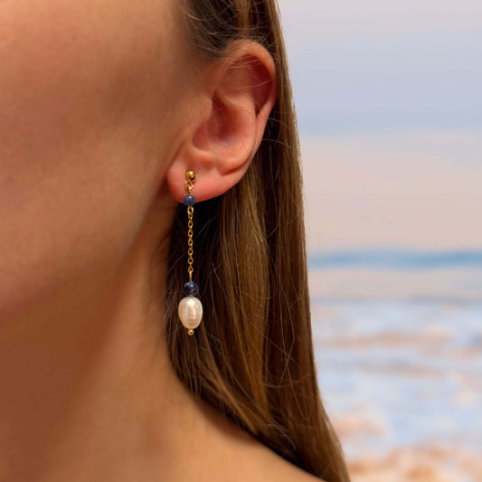 Boucles d'oreilles en acier inoxydable portés à la plage par une femme