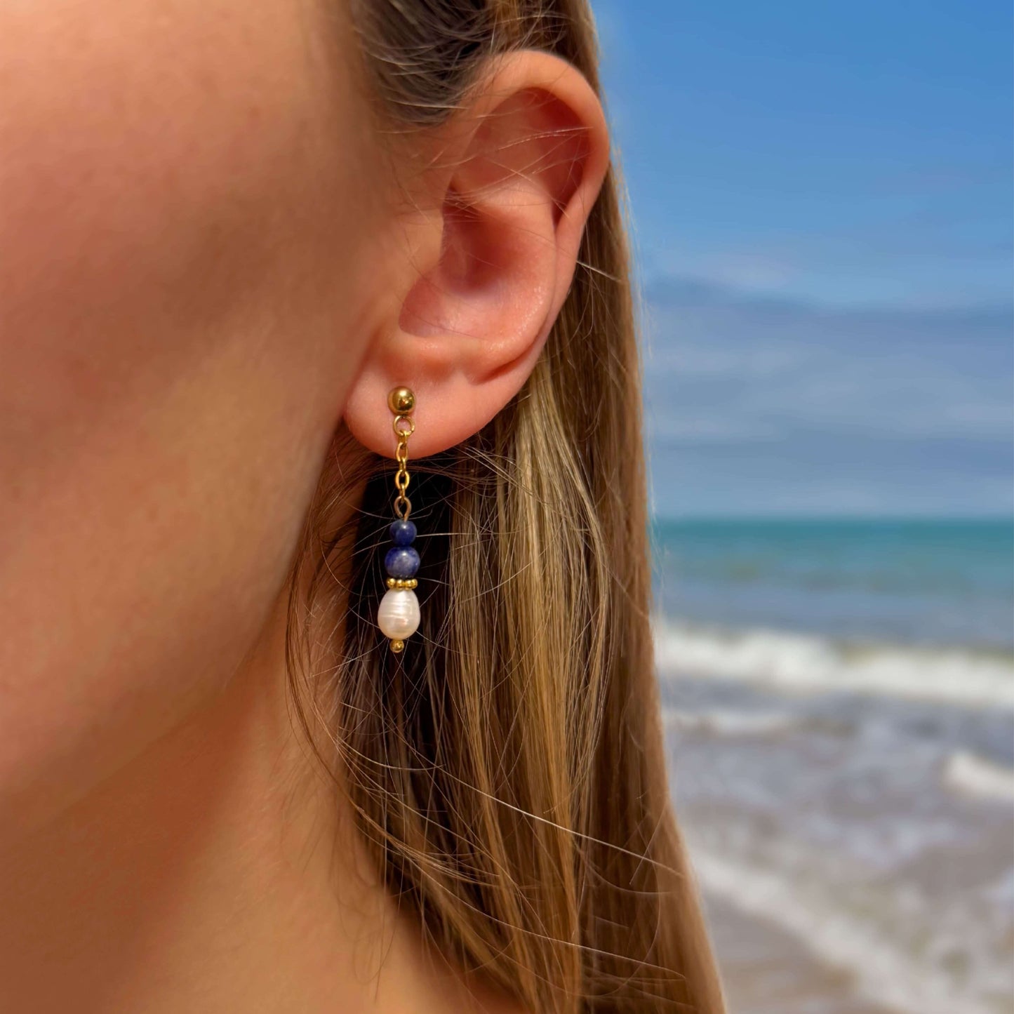 Boucles d'oreilles en acier inoxydable portées par une femme à la plage
