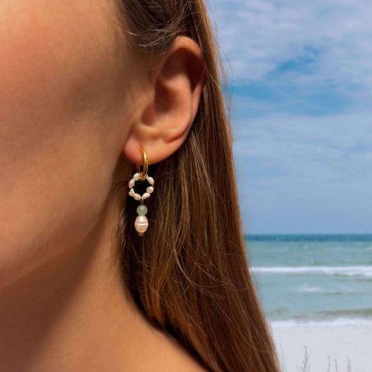 Boucles d'oreilles en perles d'eau douce portées à la plage par une femme