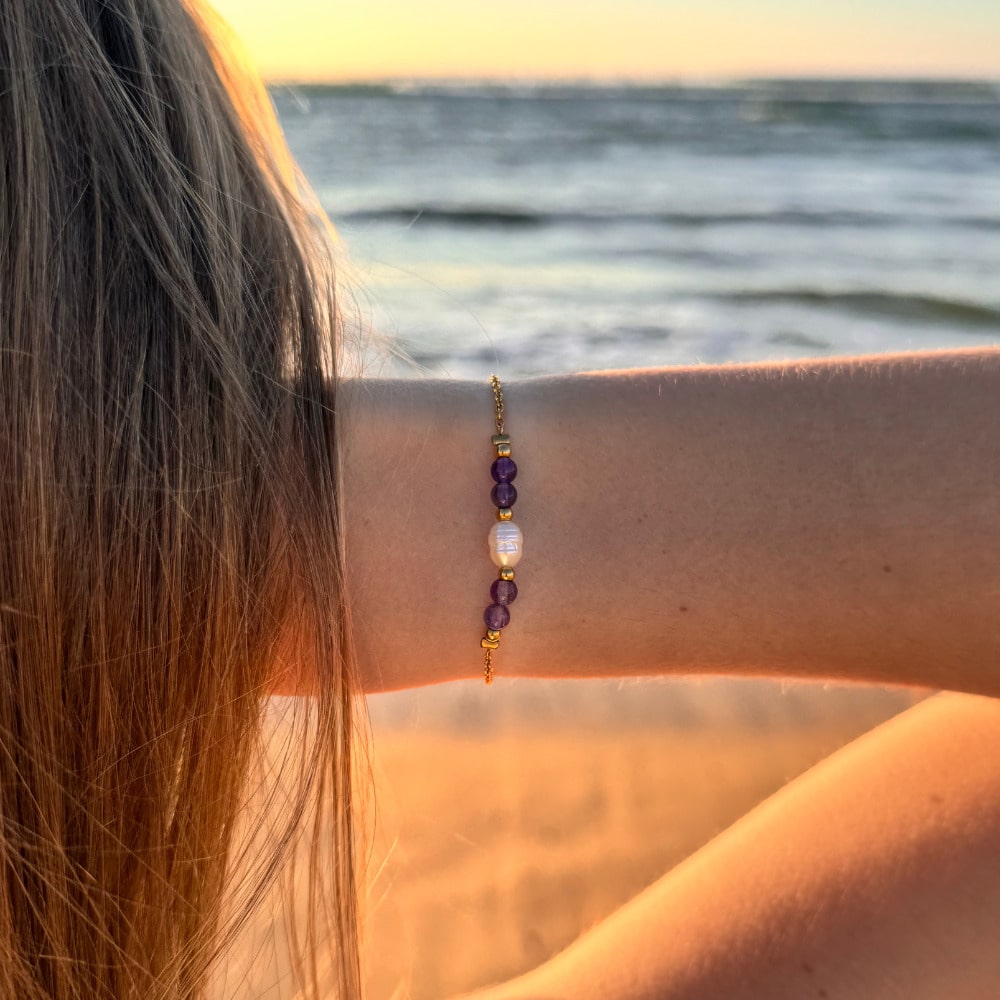 Bracelet en acier inoxydable avec perle d'eau douce et perles de couleur porté par une femme devant un coucher de soleil.