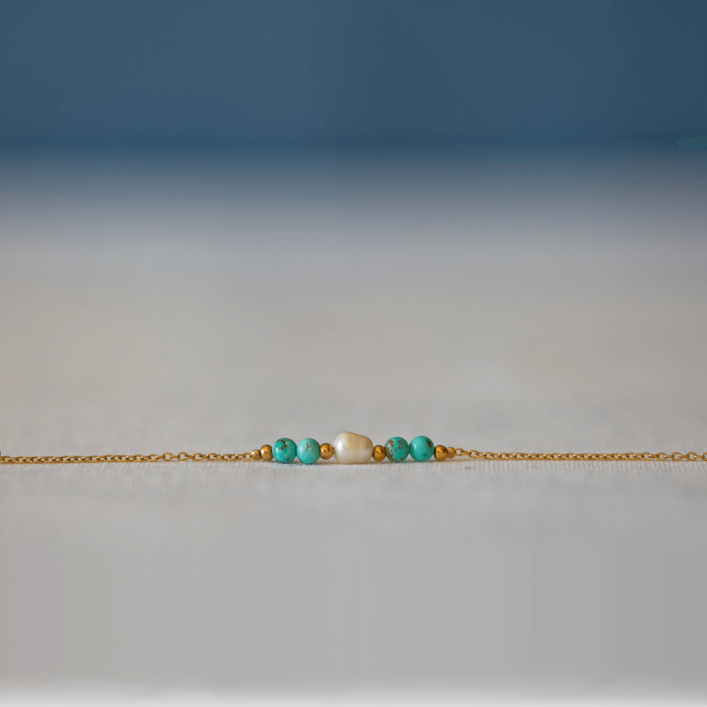 Bracelet élégant Acropora en perle d'eau douce et perles de turquoise bleu  posé sur fond gris.