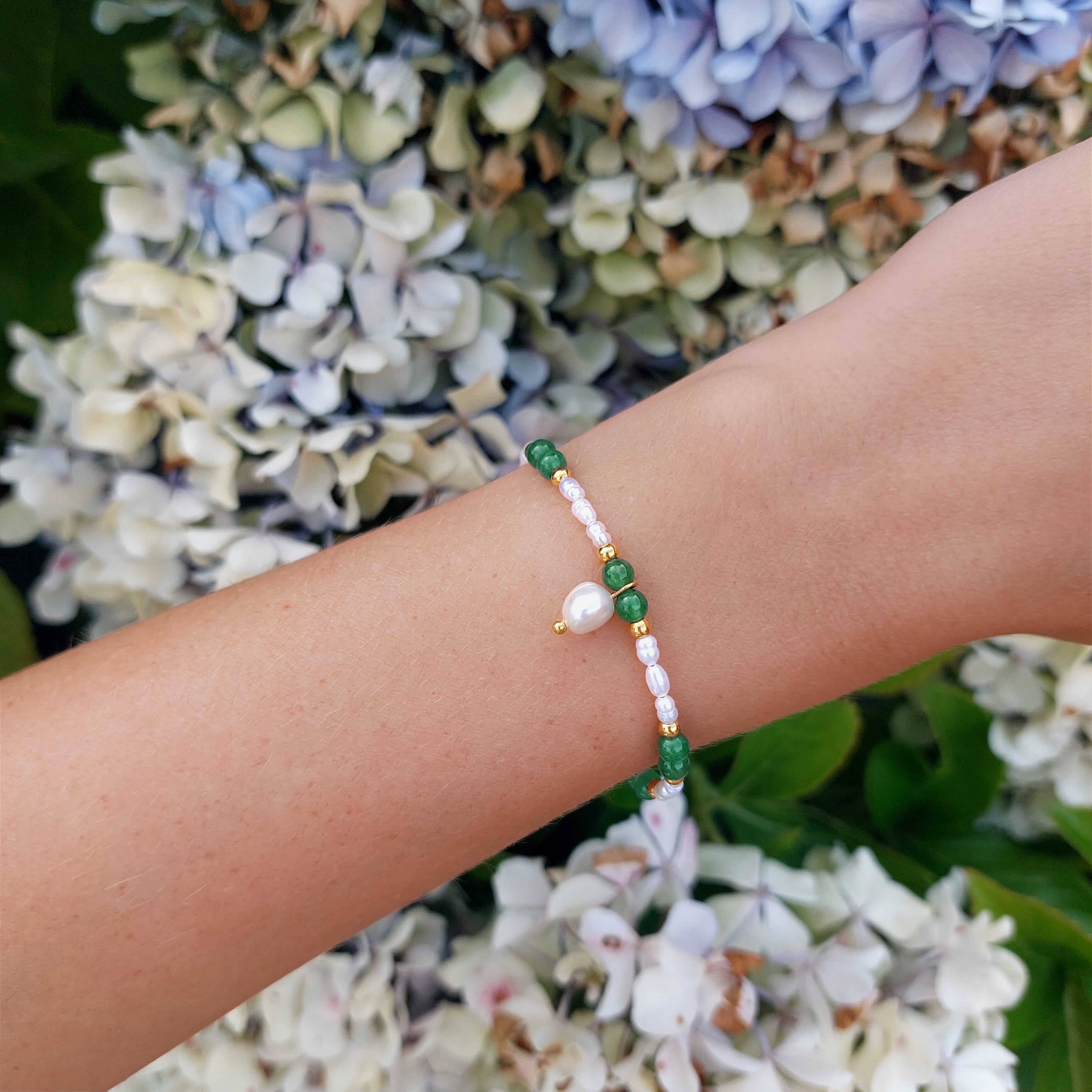 Bracelet en acier inoxydable, perles d'eau douce et pierres naturelles vertes porté par une femme.