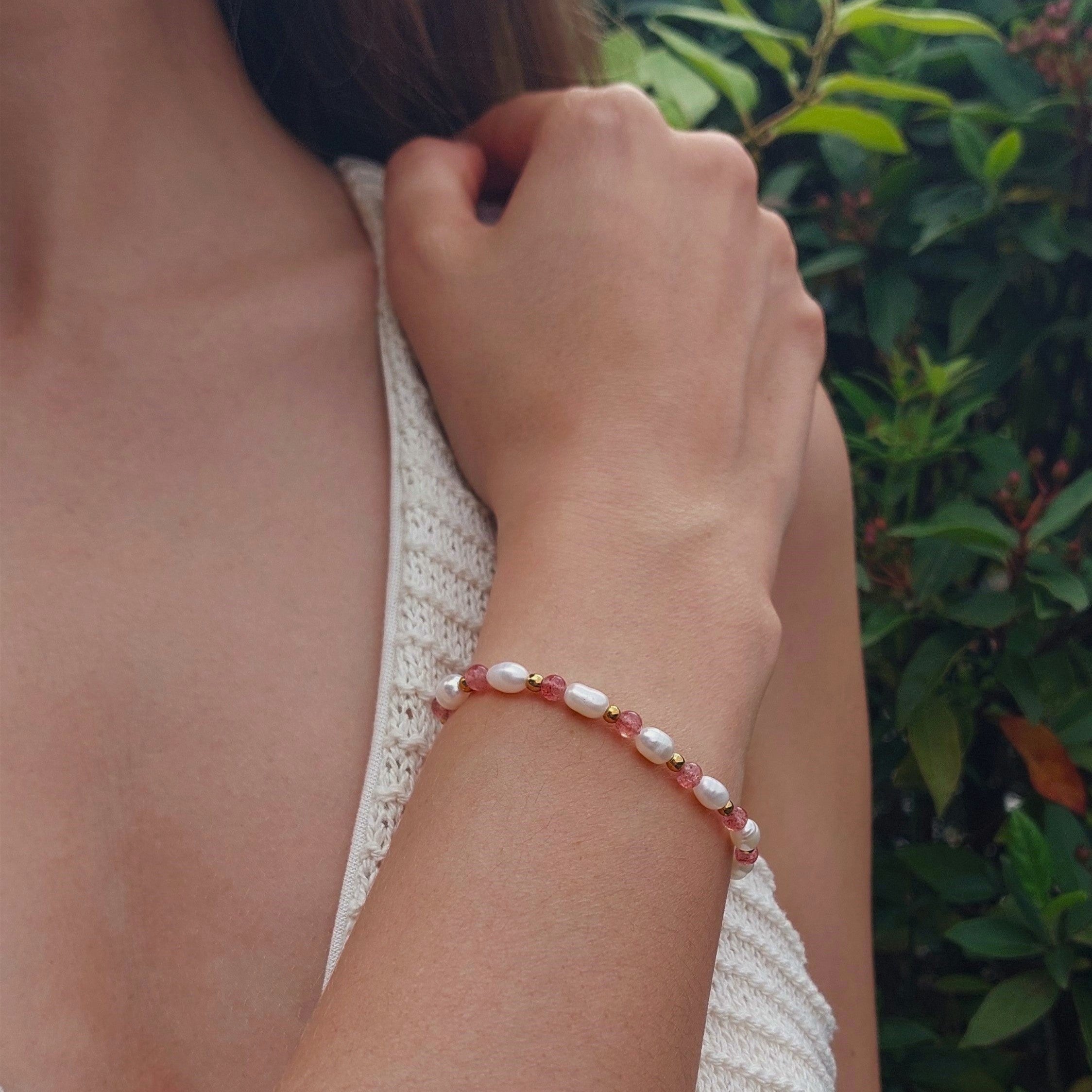 Bracelet en perles d'eau douce, pierres de quartz fraise et acier inoxydable porté par une femme