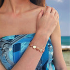 Bracelet en acier inoxydable doré avec perles d’eau douce naturelles oranges plates porté par une femme à la plage