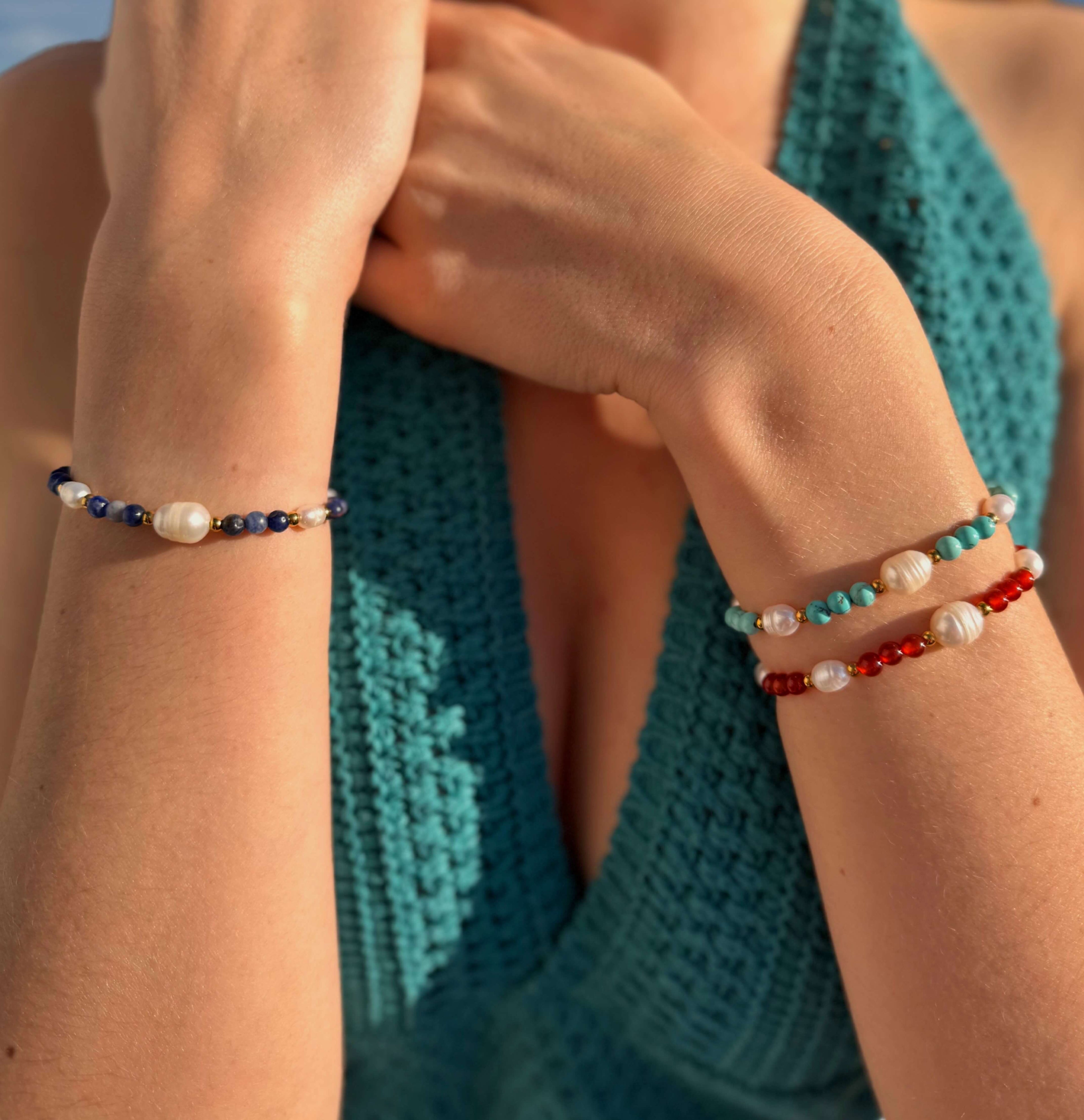 Bracelets en pierres naturelles et perles d'eau douce portés en accumulation par une femme