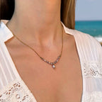 Collier porté par une femme, en acier inoxydable doré avec petites perles d’eau douce et grosse perle centrale violette.