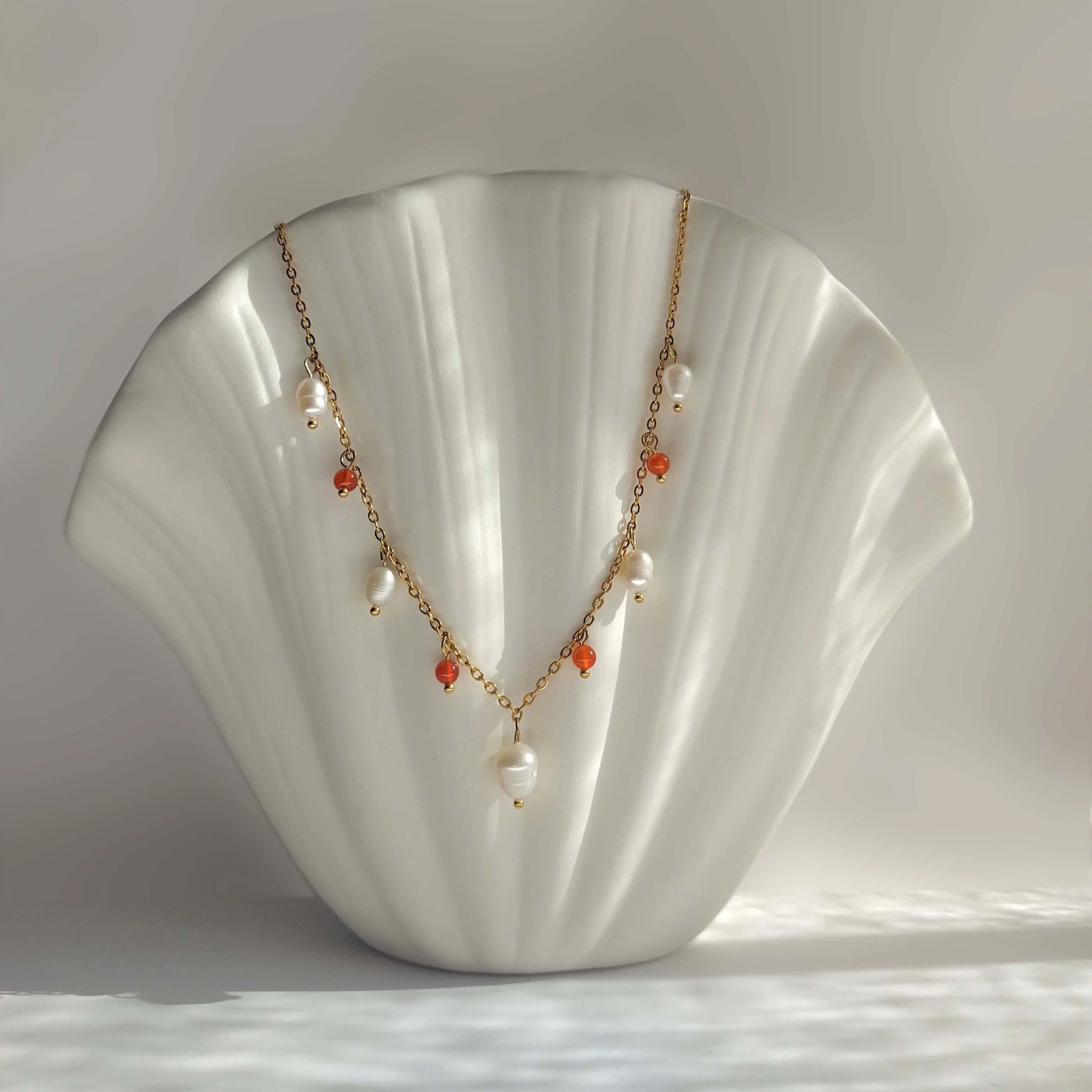 Collier Meandrina en perles d'eau douce et perles de cornaline rouge posé sur fond blanc