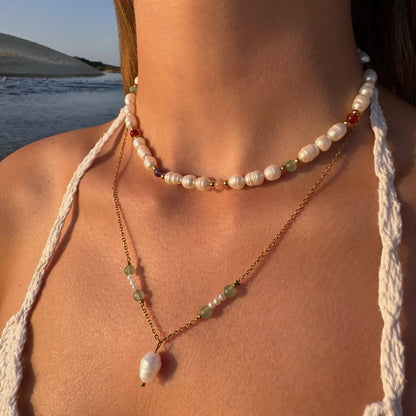 Collier ras de cou en acier inoxydable  doré avec perles d'eau douce et perles de couleur porté par une femme à la plage.