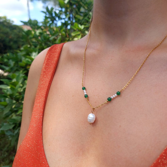 Collier en acier inoxydable avec pierres de couleur vertes et perle d'eau douce en pendentif porté par une femme.