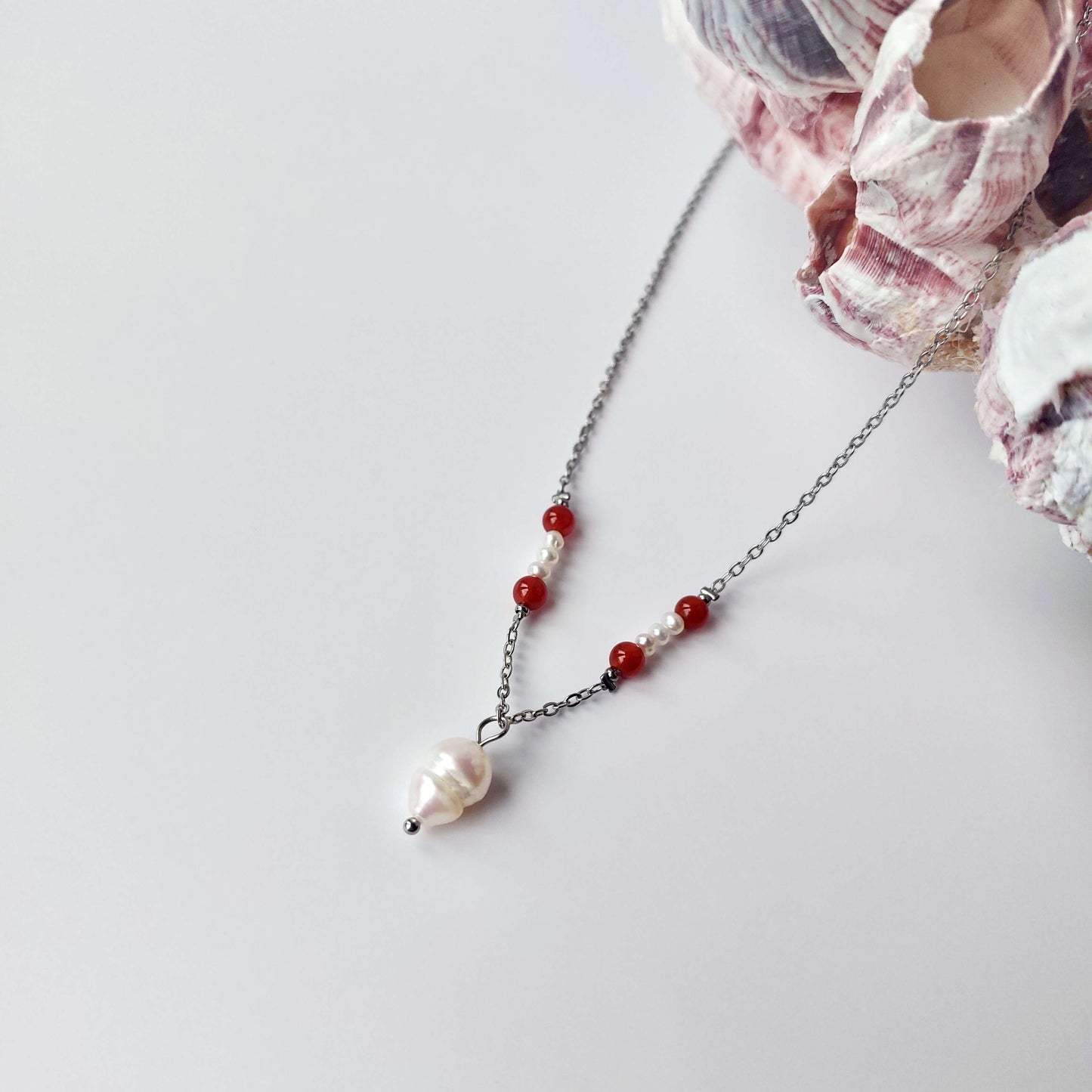 Collier élégant avec chaine en acier inoxydable argenté paré de perles d'eau douce et perles de cornaline rouge.