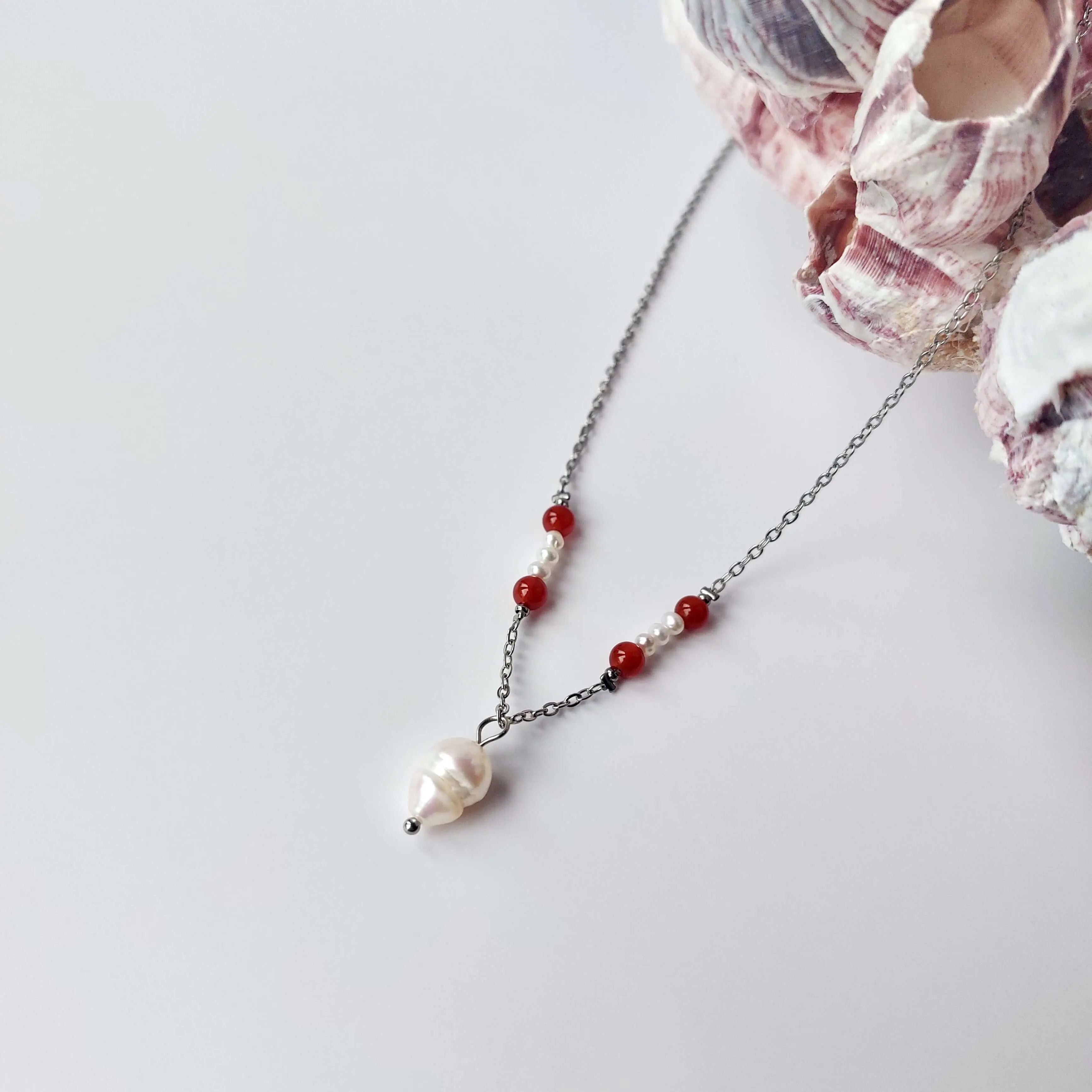 Collier élégant avec chaine en acier inoxydable argenté paré de perles d'eau douce et perles de cornaline rouge.