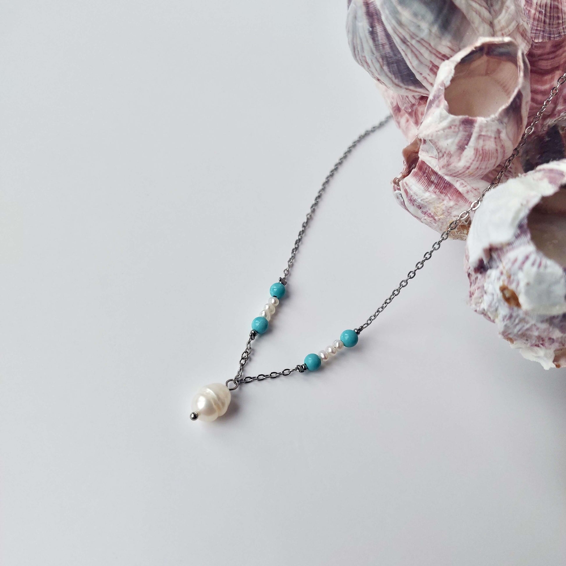 Collier élégant avec chaine en acier inoxydable argenté paré de perles d'eau douce et perles de turquoise bleue.