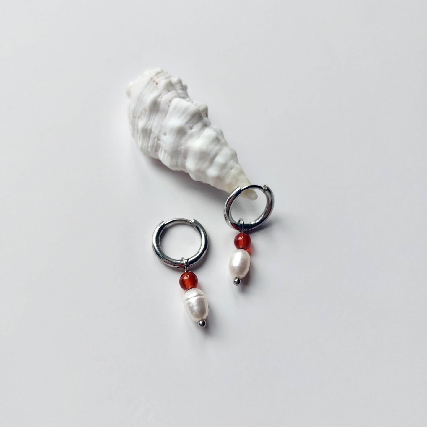 Boucles d'oreilles créoles en acier inoxydable argenté avec une pierre d'eau douce et une perle de cornaline. Design minimaliste et coloré.