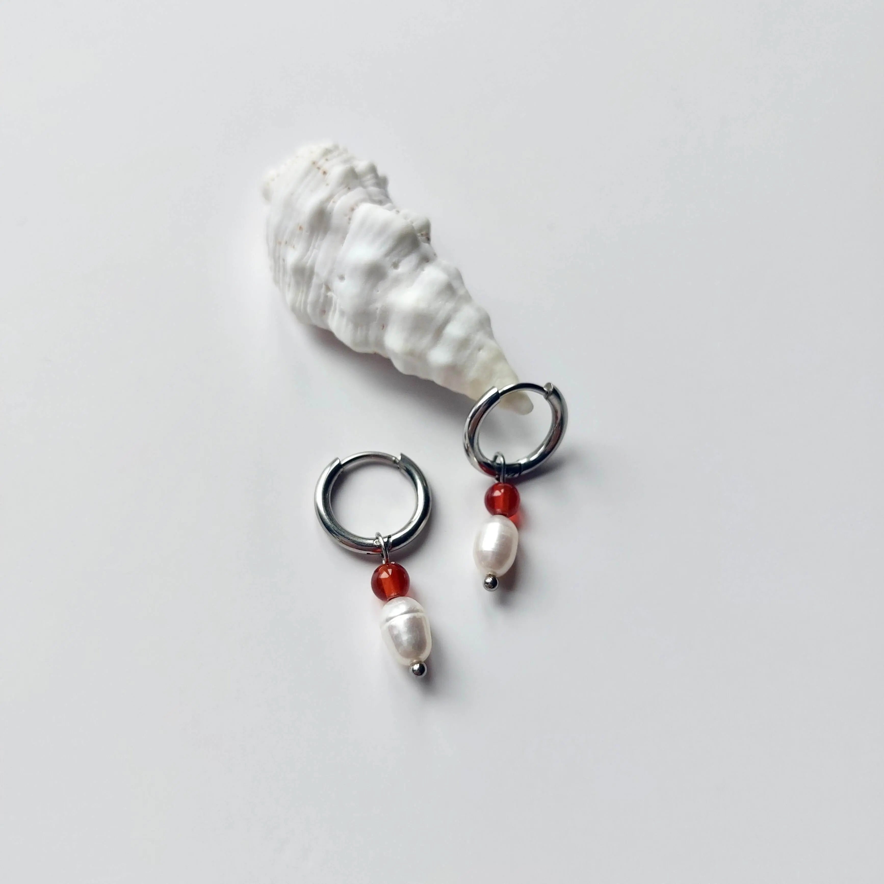 Boucles d'oreilles créoles en acier inoxydable argenté avec une pierre d'eau douce et une perle de cornaline. Design minimaliste et coloré.