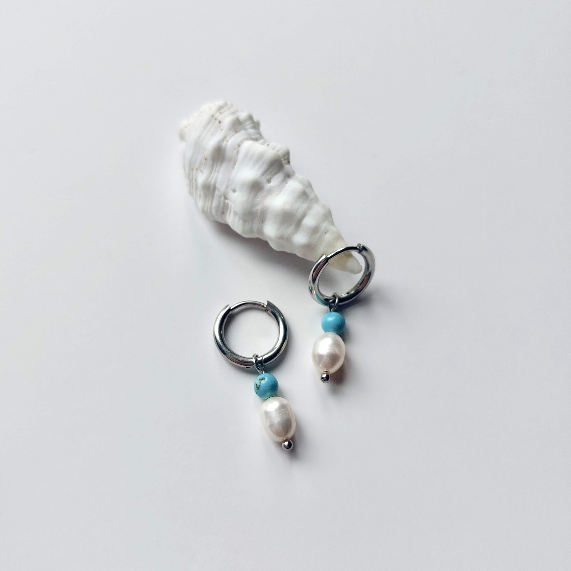 Boucles d'oreilles créoles en acier inoxydable argenté avec une pierre d'eau douce et une perle de turquoise. Design minimaliste et coloré.