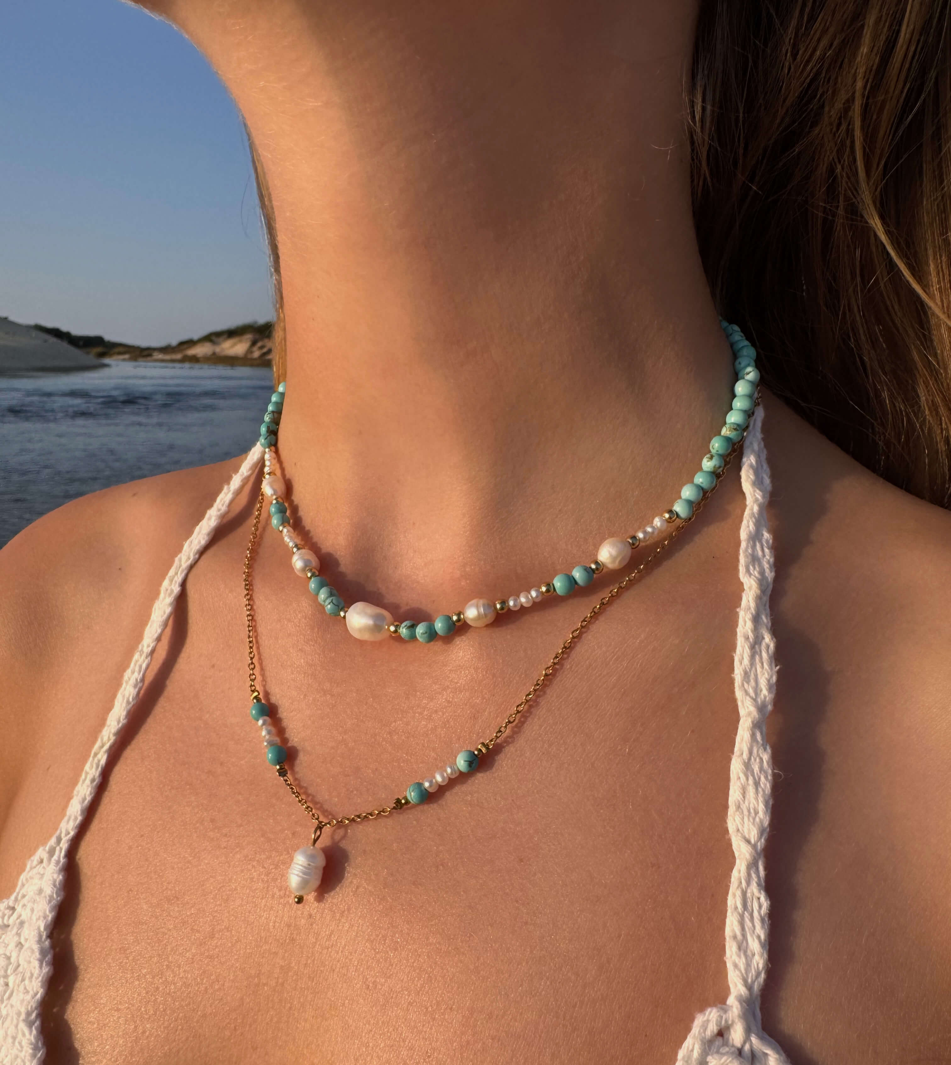 Collier ras de cou en perles d'eau douce et pierres de turquoise porté par une femme à la plage