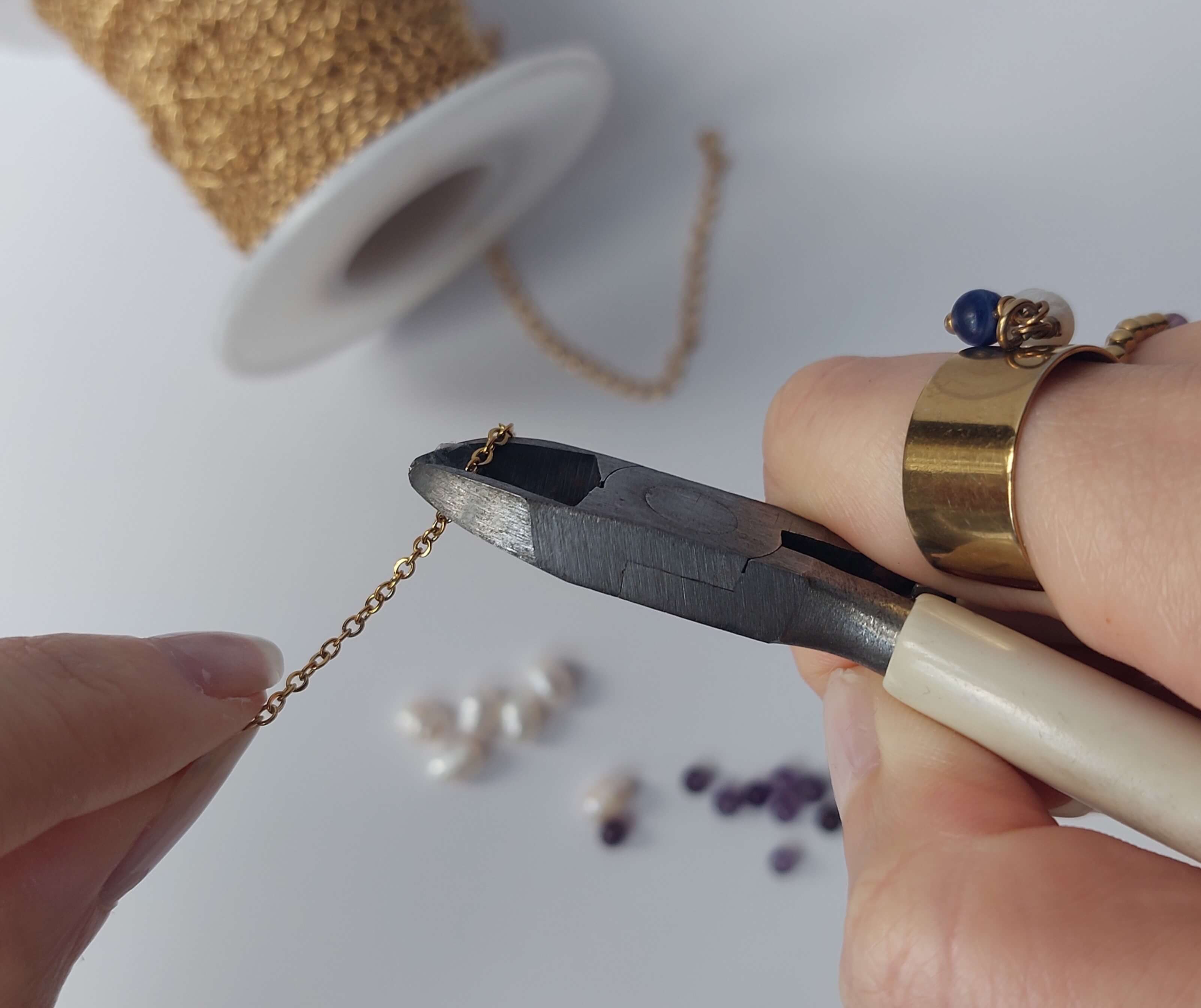 Des mains tenant une pince qui coupe une chaine en acier inoxydable