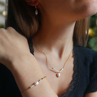 Parure de trois bijoux en acier inoxydable dore et perles deau douce porte par une femme